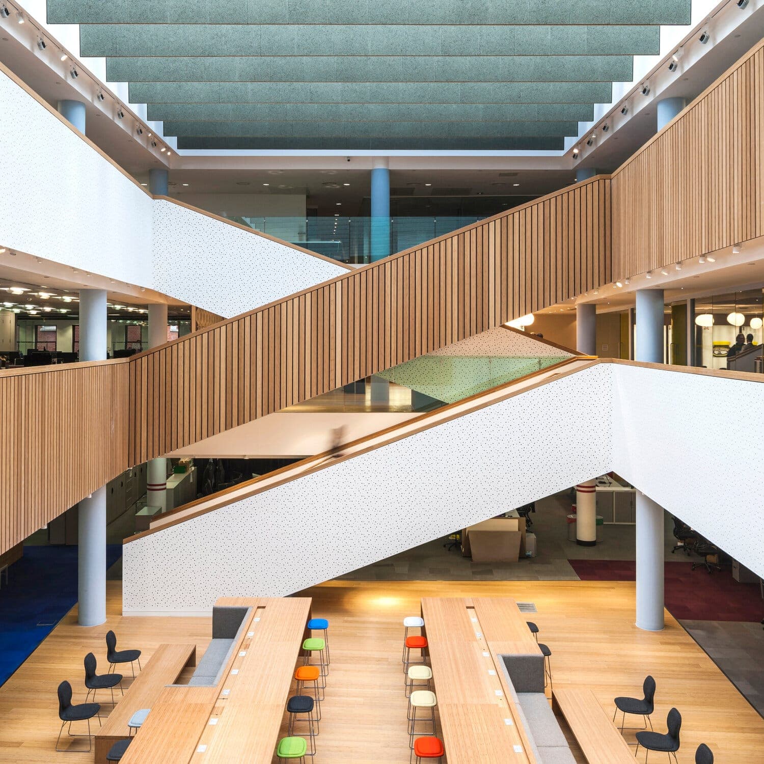Atrium staircases with slatted bamboo balustrades crossing above long bamboo worktables