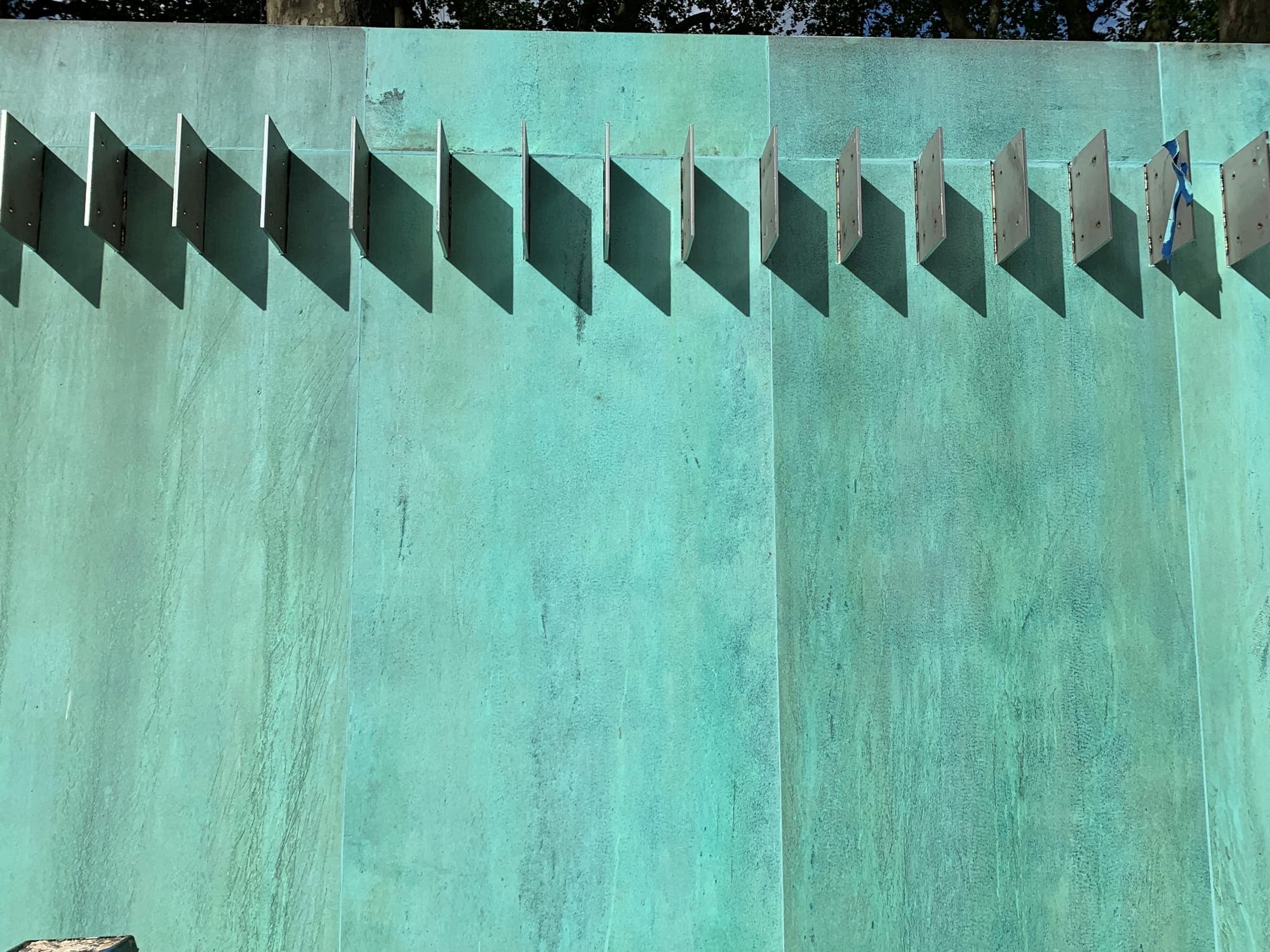 Oxidised copper panels in blue-green verdigris, their top edge cut into a row of teeth