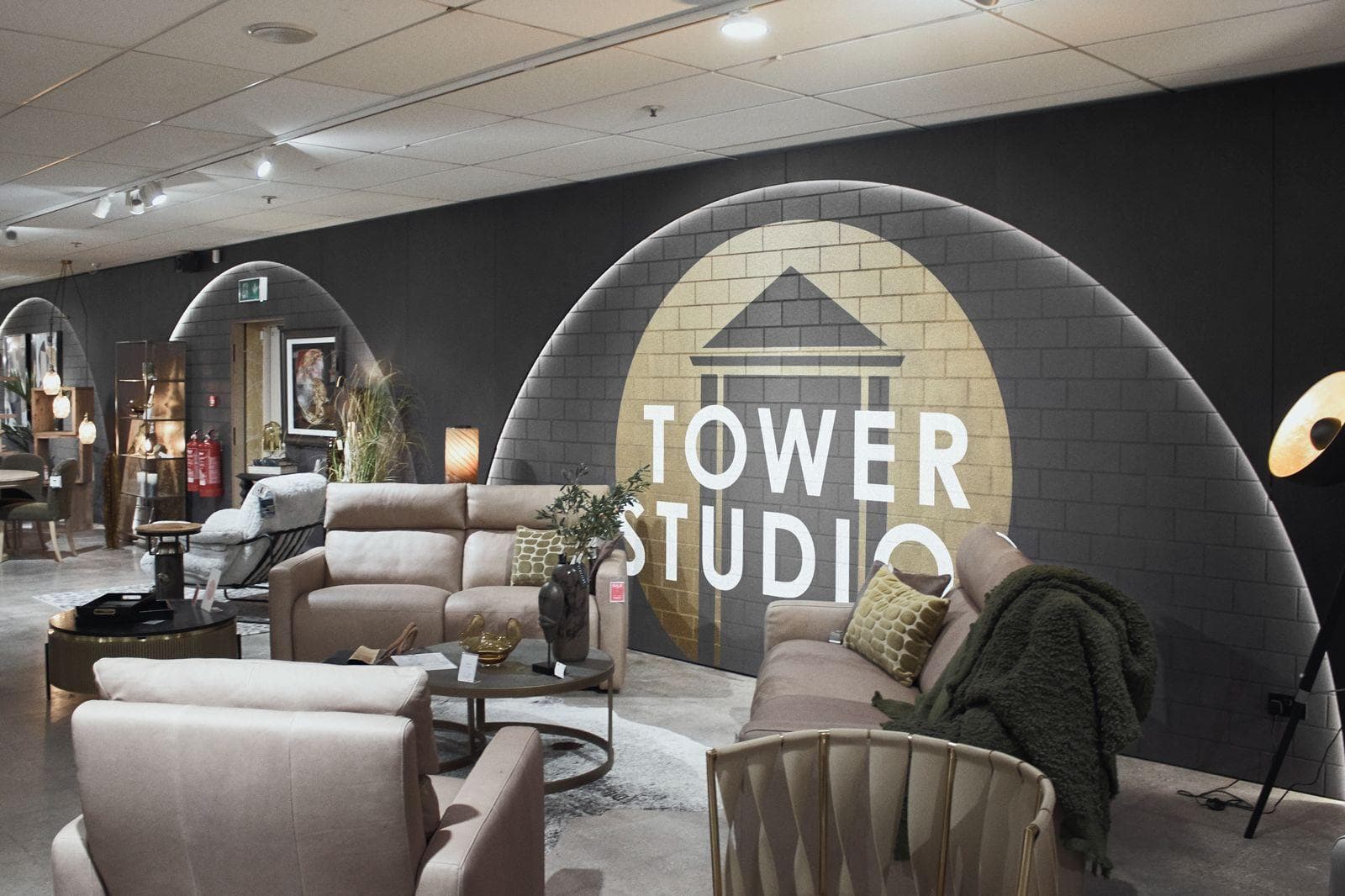 Sofas in front of a dark brick-pattern wall with backlit arches and the Tower Studio sign