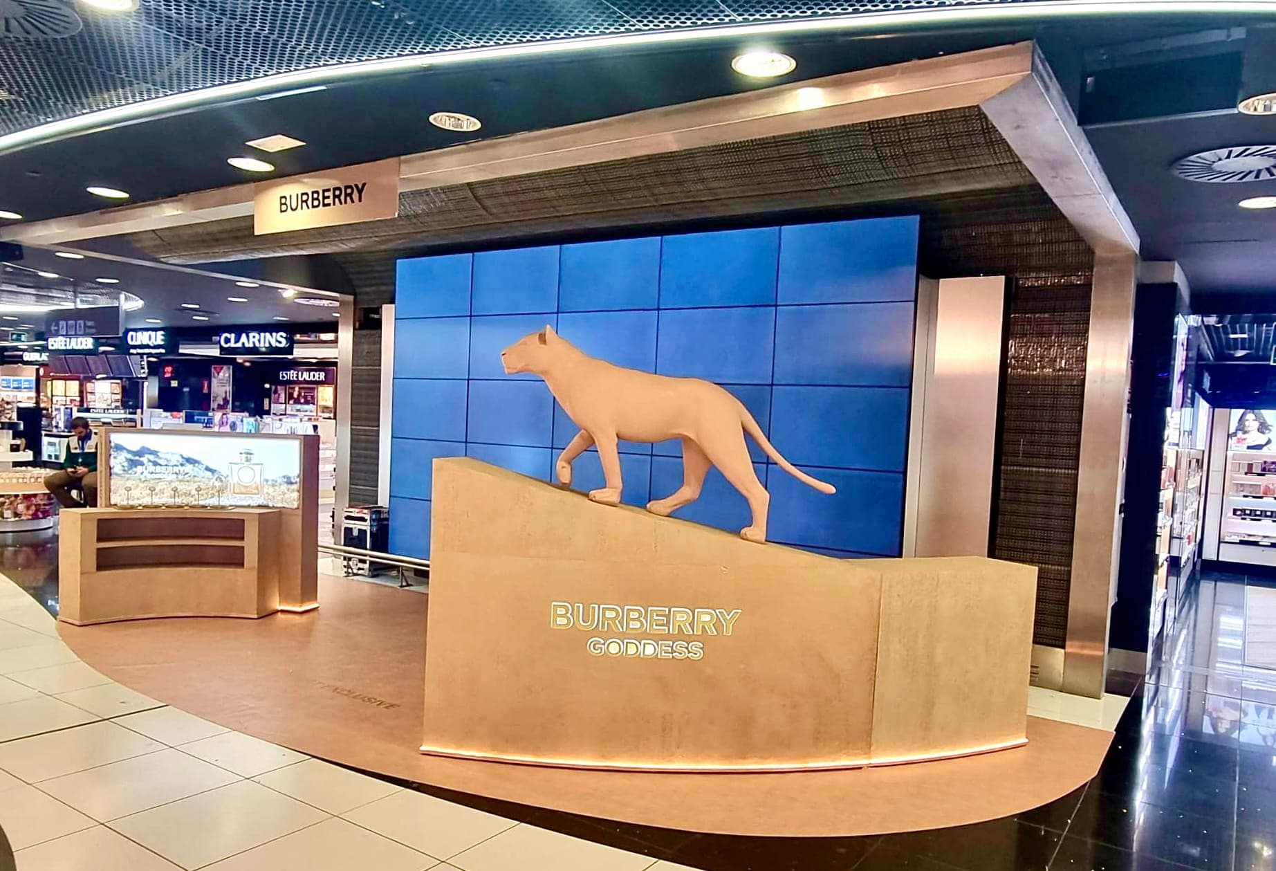 Curved pink stone-clad counter carrying a lioness sculpture in front of a blue display wall