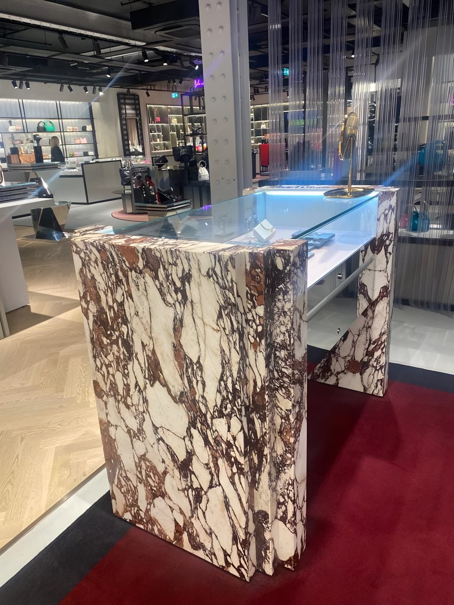 Retail counter wrapped in red-veined Calacatta marble veneer