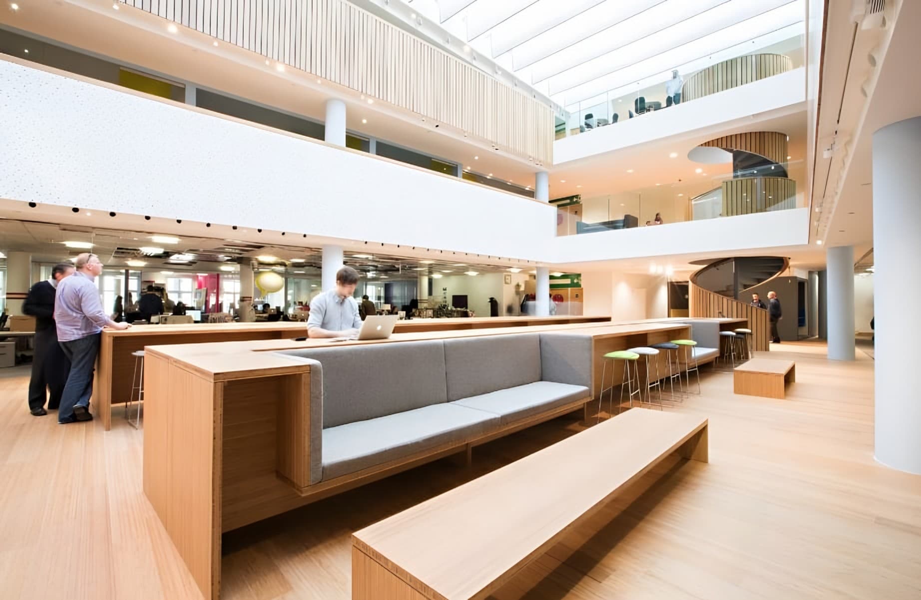 Open-plan office atrium with bamboo bench seating and flooring