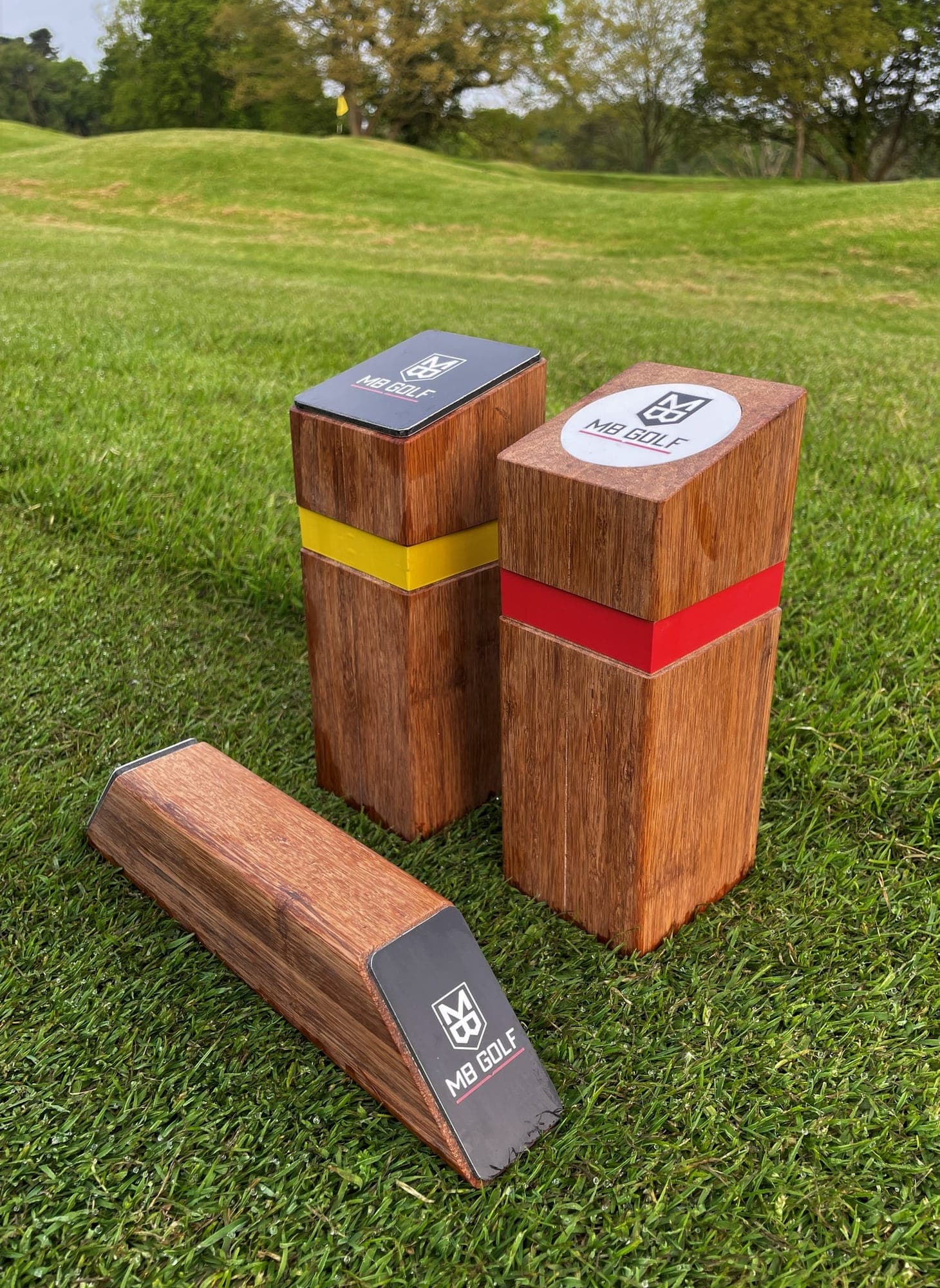 Bamboo tee-marker blocks with coloured bands and printed badges, set on the grass