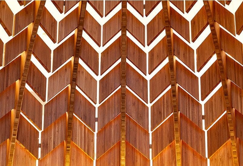 Close view of the bamboo pod skin: overlapping chevron-cut slats glowing from within