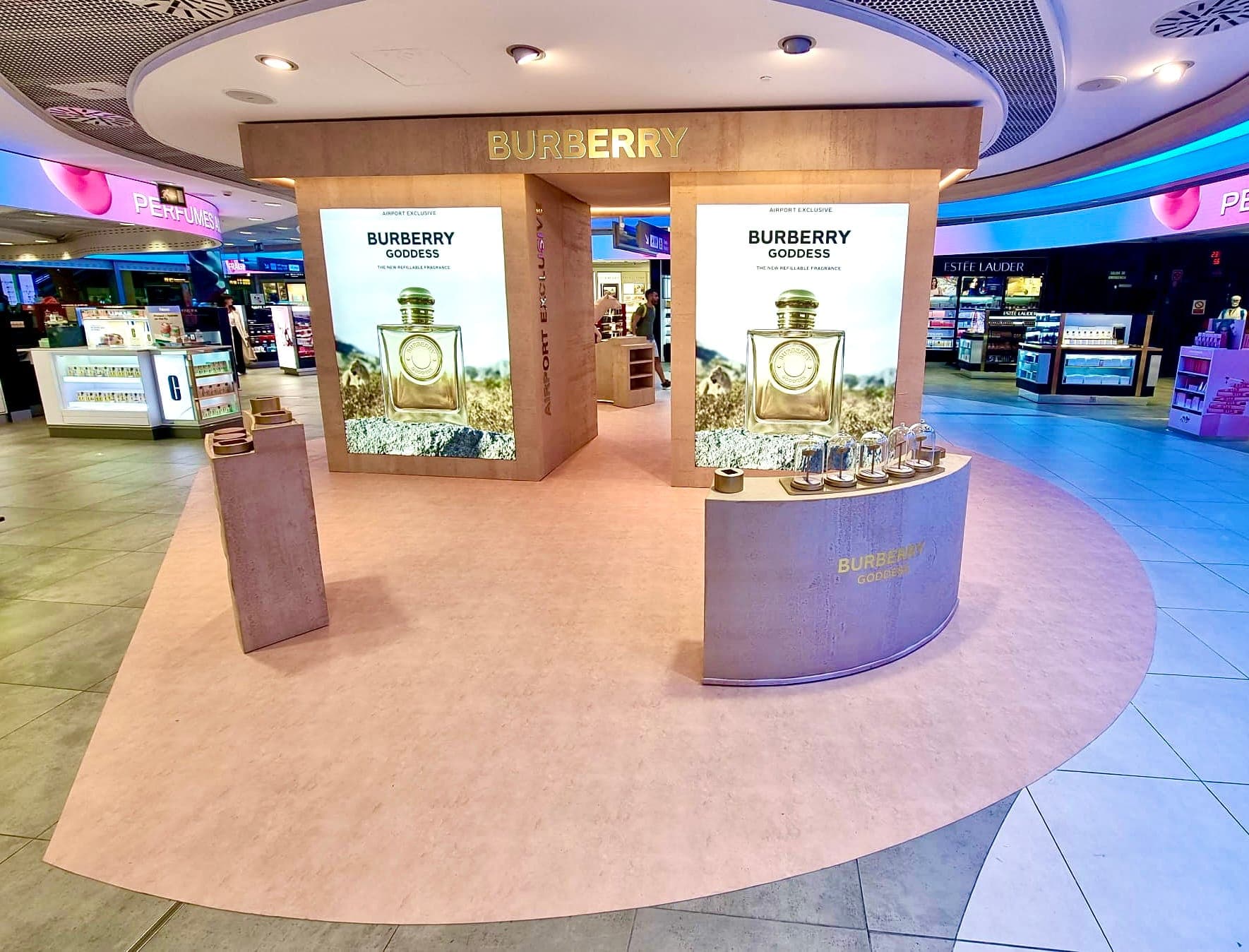 Island stand of pink stone-clad plinths and light boxes on a round pink floor