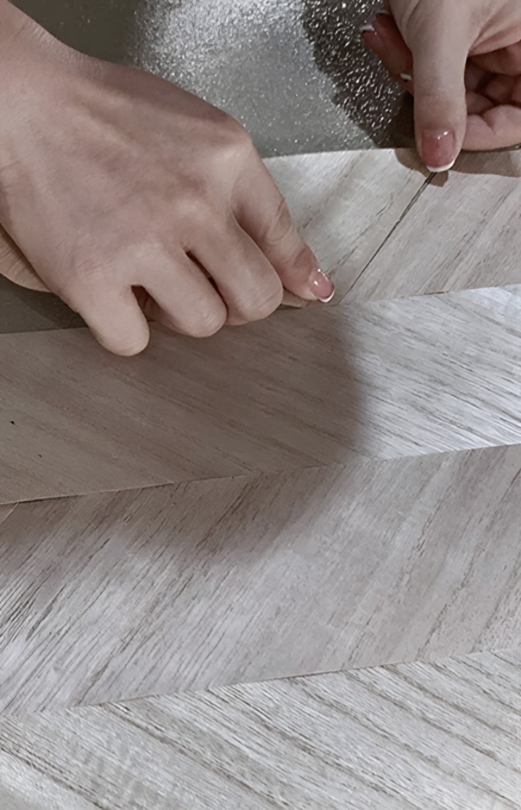 Hands laying a chevron wood-effect wallcovering