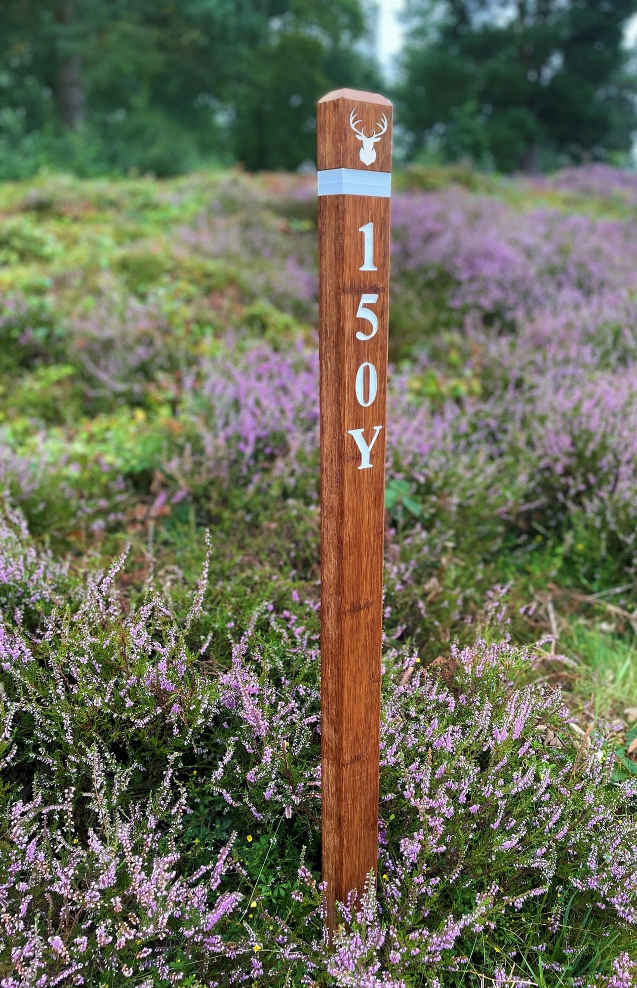 A slim bamboo post marked 150 yards, standing in flowering heather