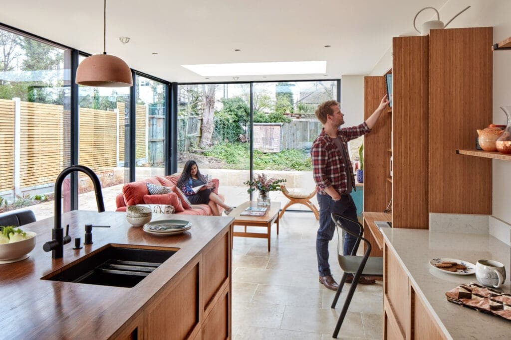 Open-plan kitchen with a bamboo island and tall bamboo cupboards, the garden beyond