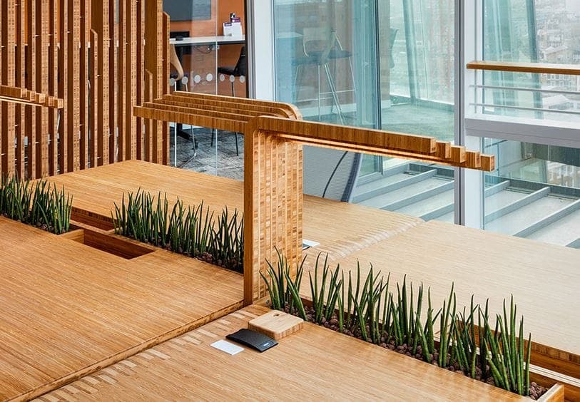 Bamboo decking and planters beneath a slatted bamboo frame beside floor-to-ceiling glazing
