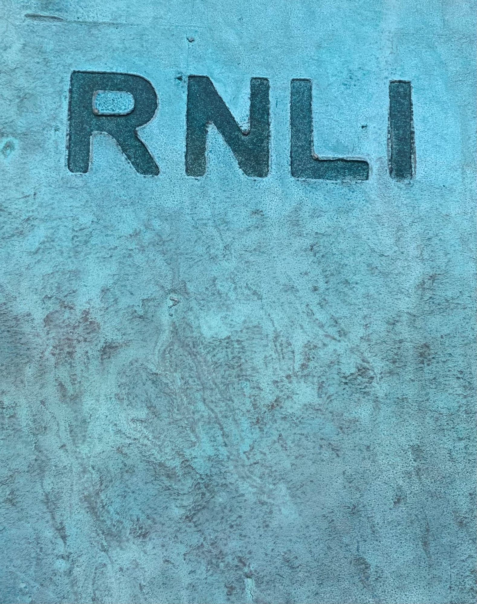 RNLI lettering pressed into a verdigris copper panel
