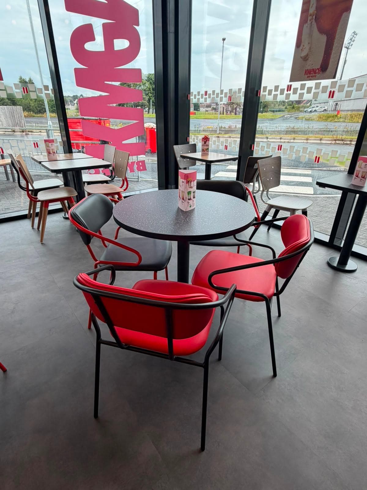 Round table with red upholstered chairs beside a glazed shopfront