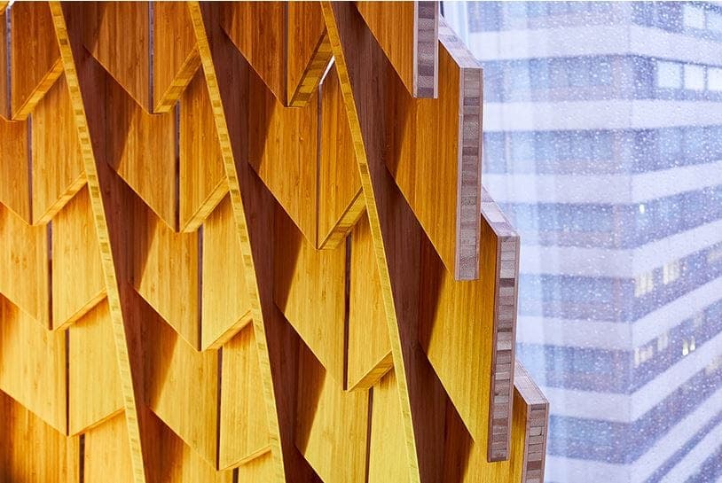 Chevron bamboo slats of a pod against a neighbouring tower seen through the glass