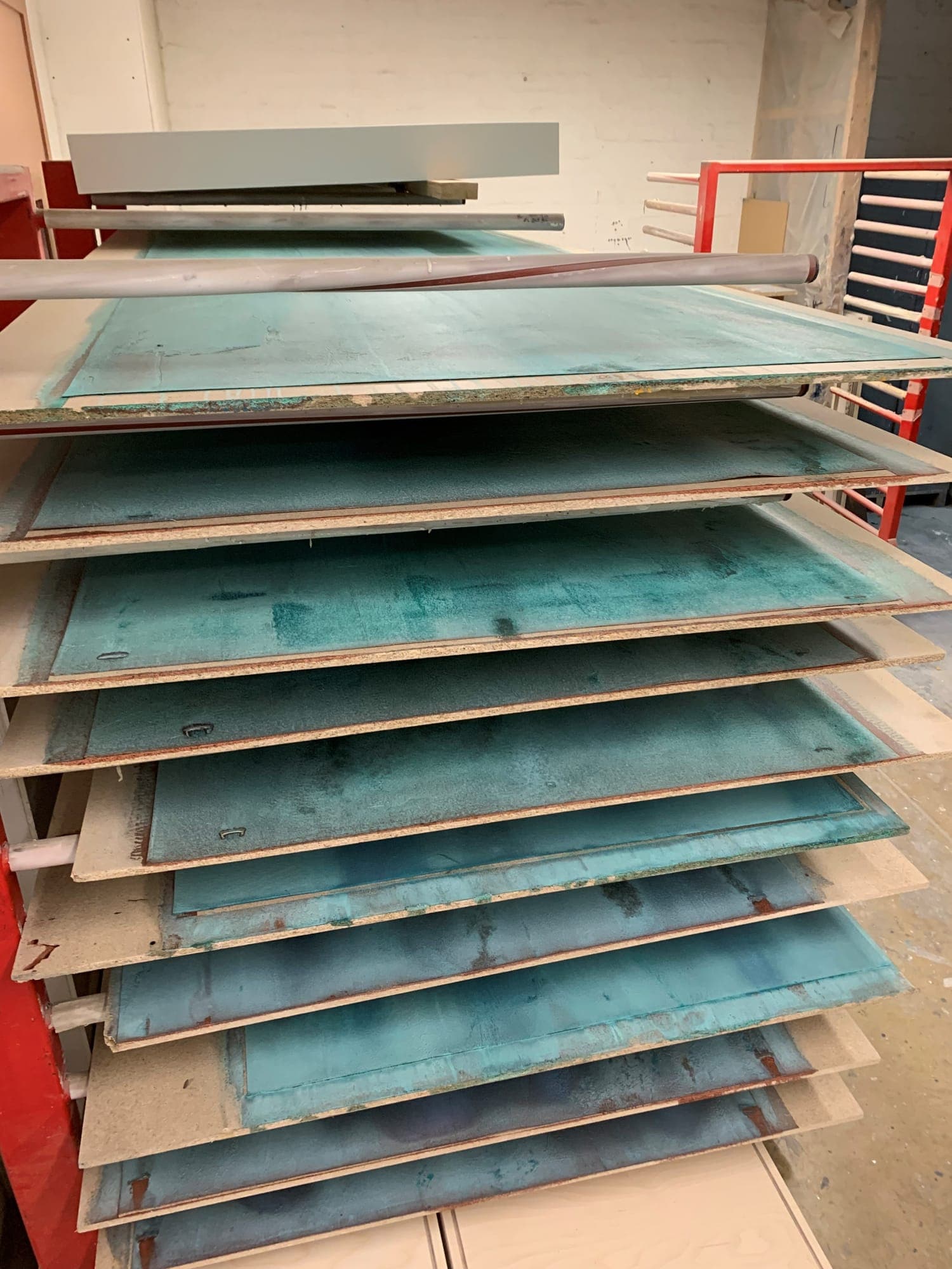 Copper-finished panels stacked on a drying rack in the workshop