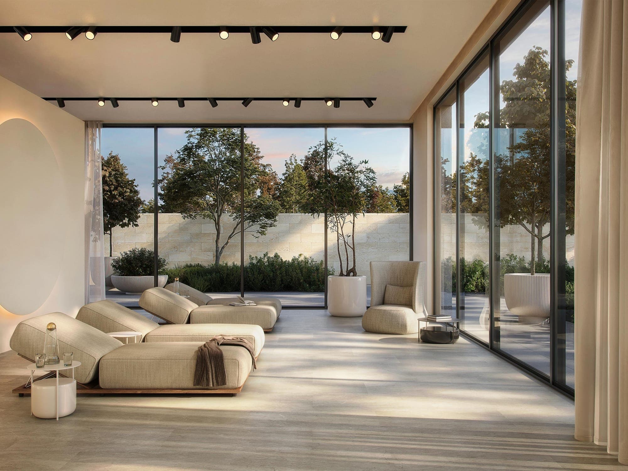 Glazed lounge opening onto a garden, with cream daybeds on a light marble-effect floor