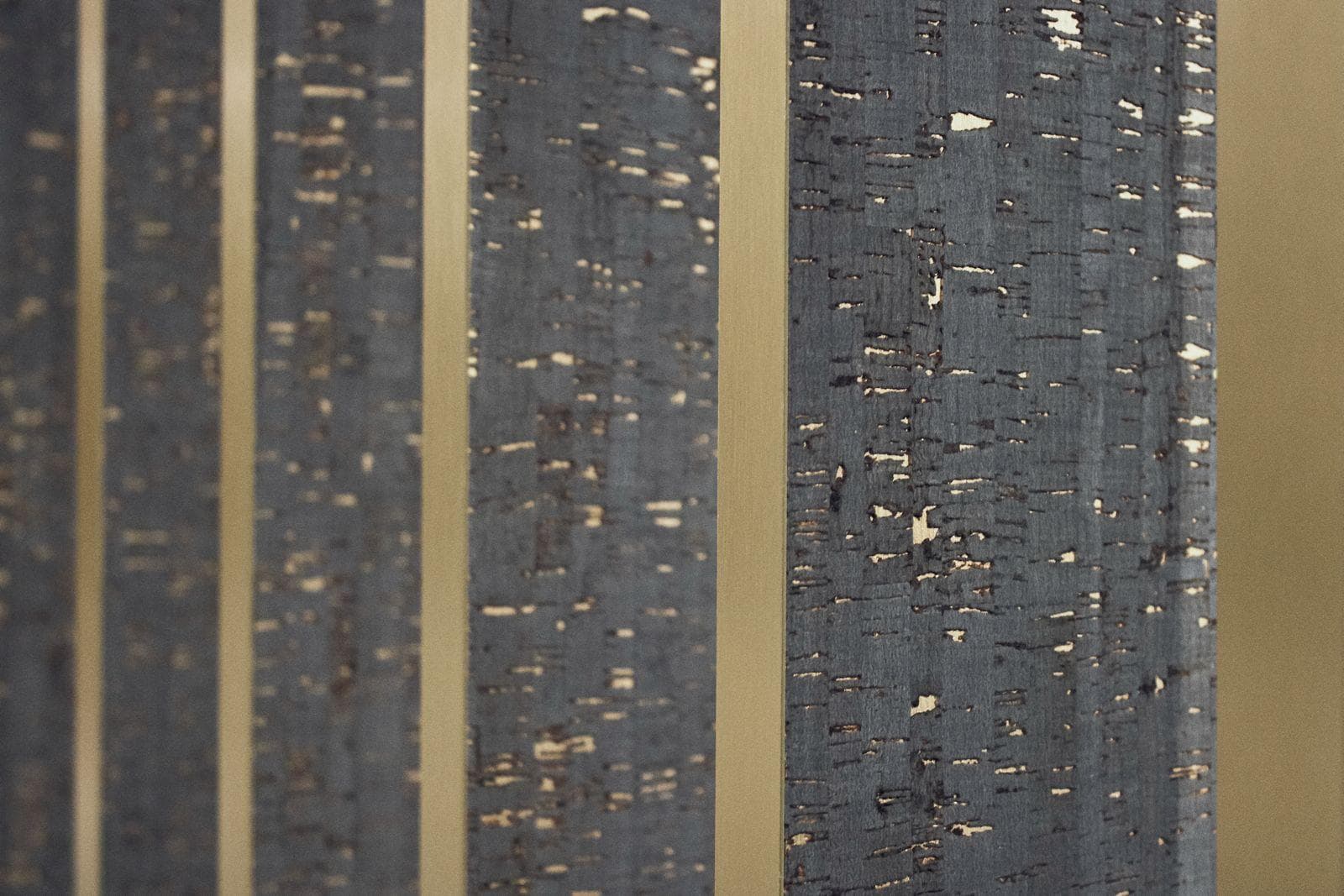 Close-up of dark flecked slats separated by brushed brass strips