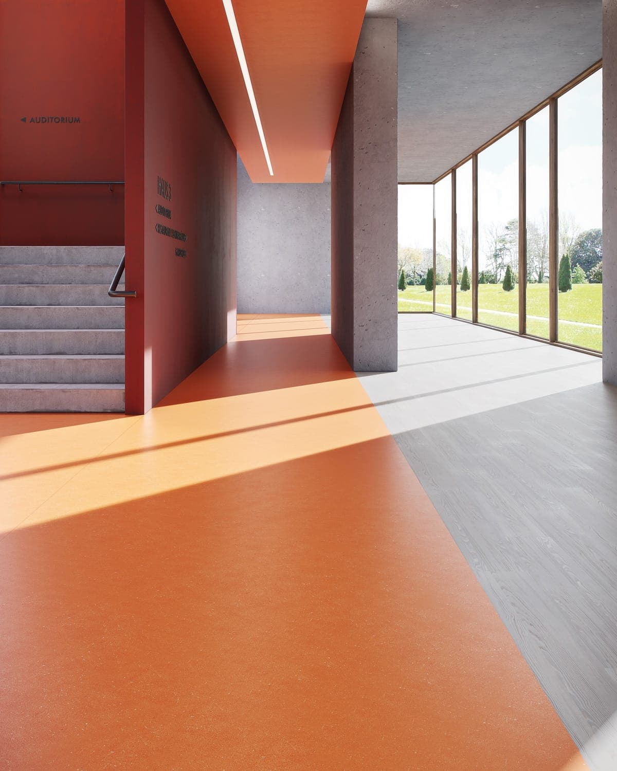 Sunlit corridor beside a stair, with an orange floor meeting a grey wood-effect floor
