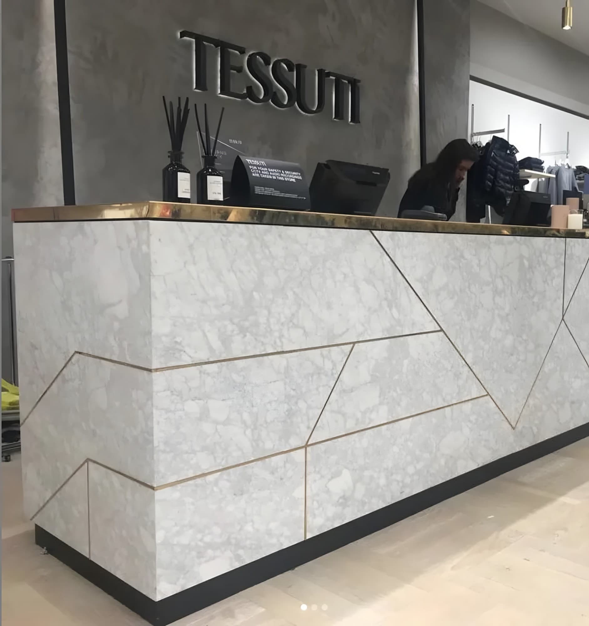 Reception desk clad in white marble veneer with brass inlay lines
